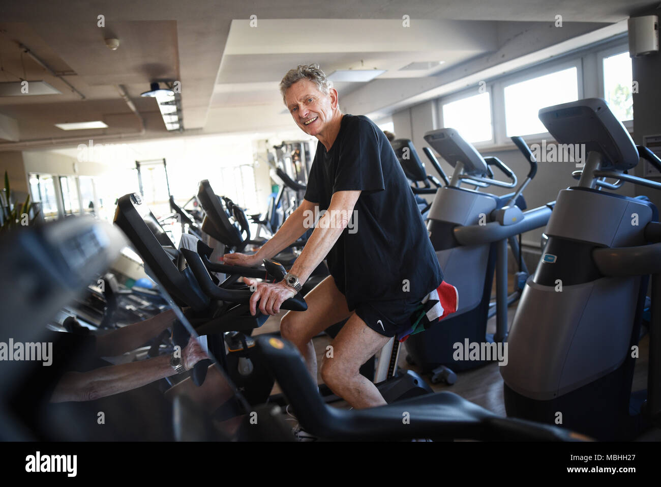 06 April 2018, Germany, Bergisch Gladbach: Clemens Berghaus, 73 years old, exercises on a bicycle ergometer at a gym. Photo: Henning Kaiser/dpa Stock Photo