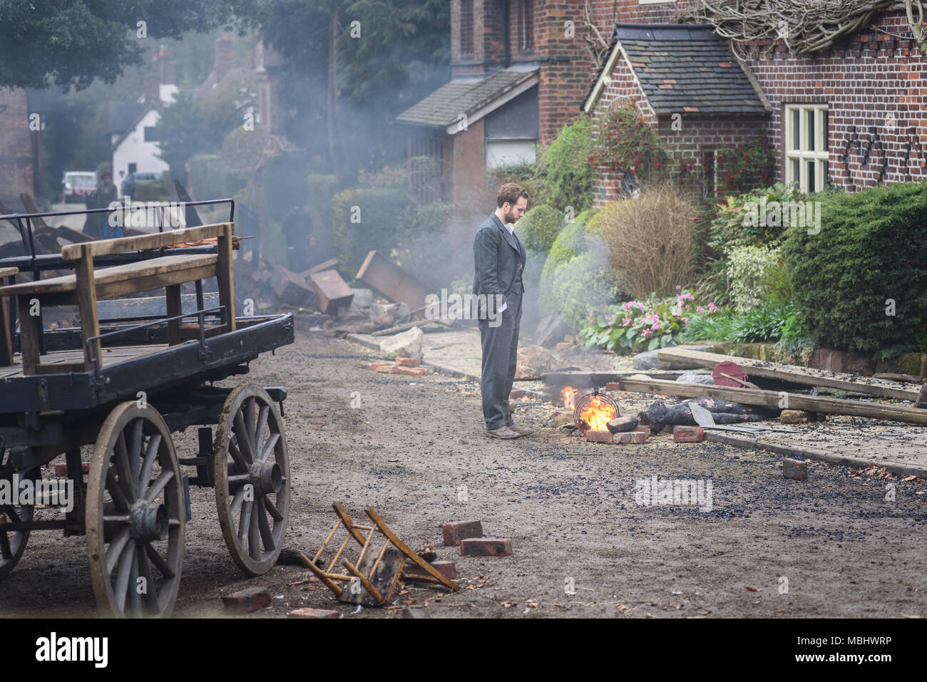Great Budworth, UK. 11th April, 2018. Actor Rafe Spall dressed in Edwardian costume, playing the lead role of George, looks on at the carnage in the new BBC drama 'War Of The Worlds' by HG Wells, filmed in the streets of Great Budworth village, Cheshire on Wednesday afternoon, April 11th. Credit: Ian Hubball/Alamy Live News Stock Photo
