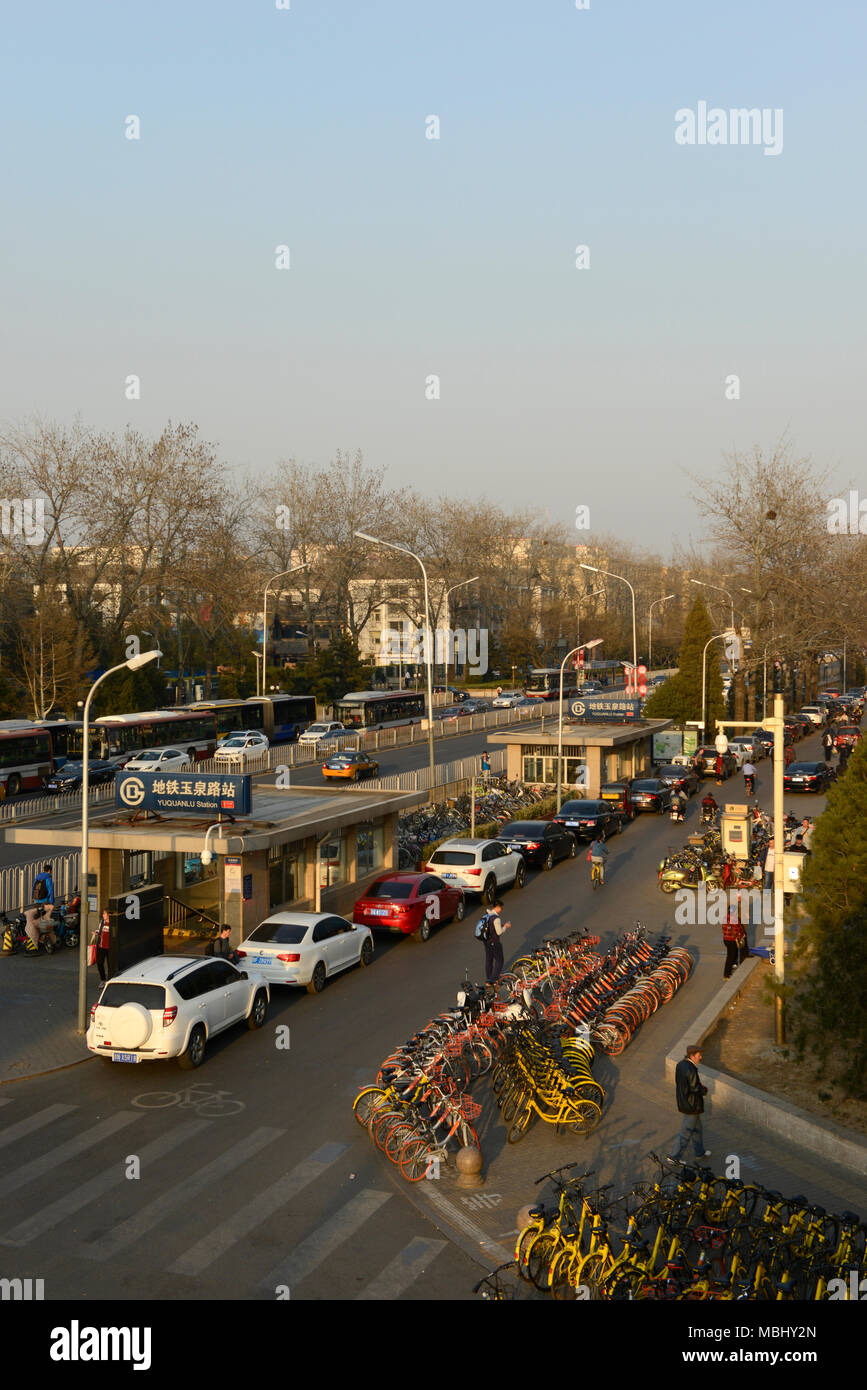 Cars and bicycles are parked by the Yuquan road Metro station on Fuxing Road in central western Beijing, China as rush hour approaches Stock Photo