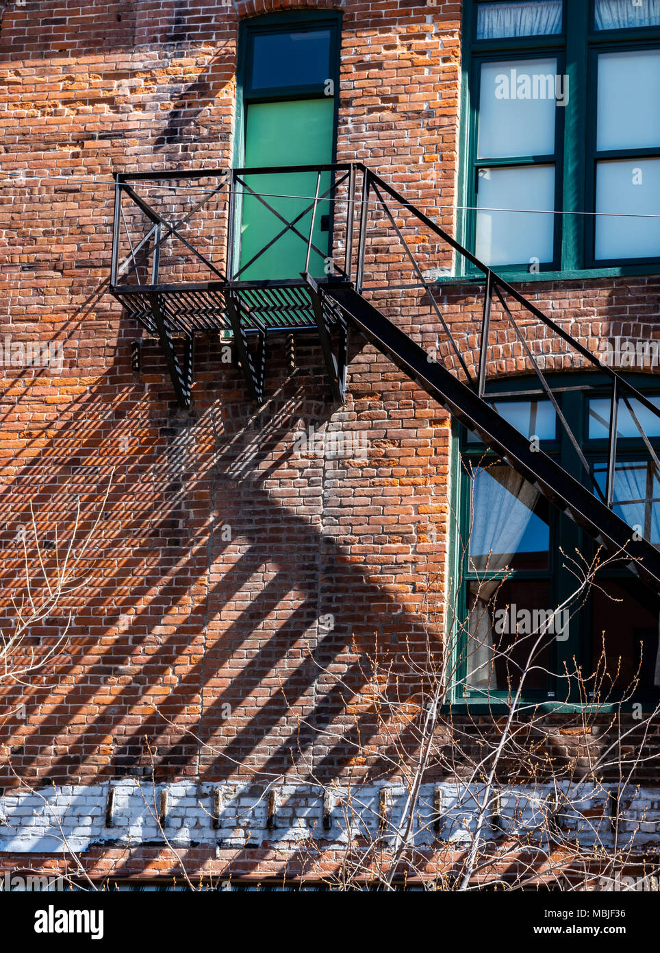 Iron fire escape casts graphic shadows on historic brick building; National Historic District; Salida; Colorado; USA Stock Photo