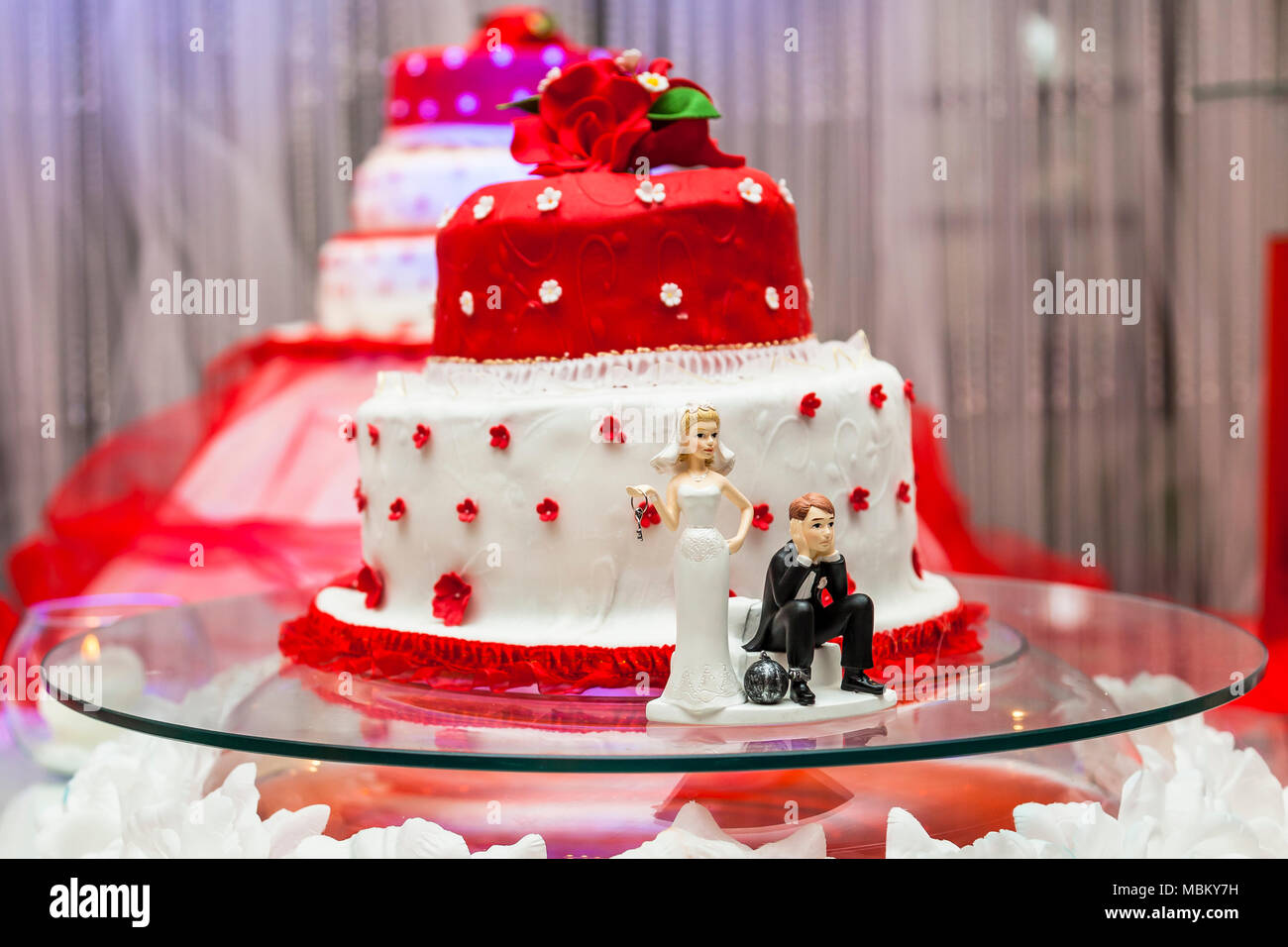 Figurines On Bottom Of Red And White Wedding Cake Stock Photo