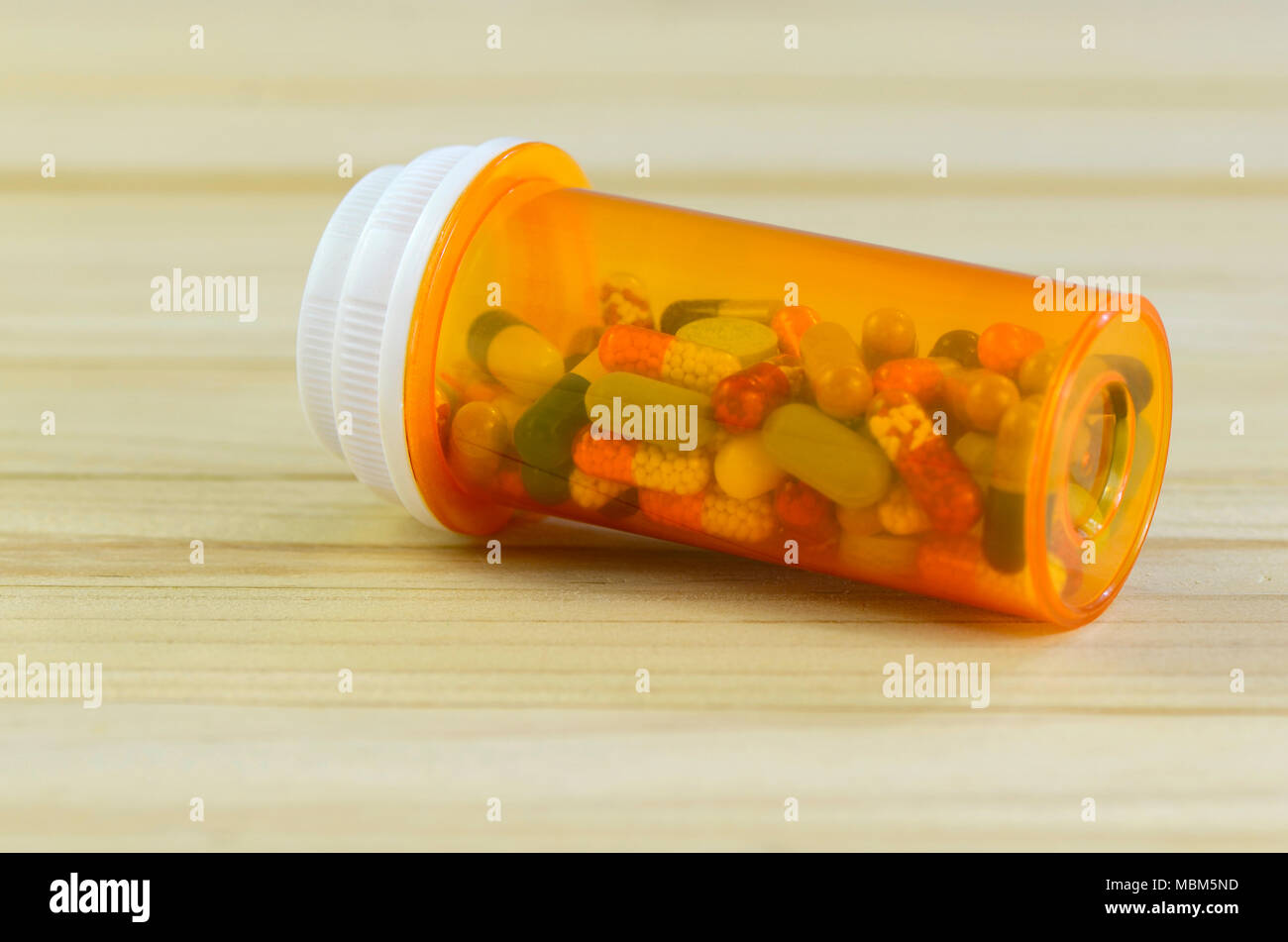 Oral medications in light protected bottle on pine wood table. Protect from light. Stock Photo