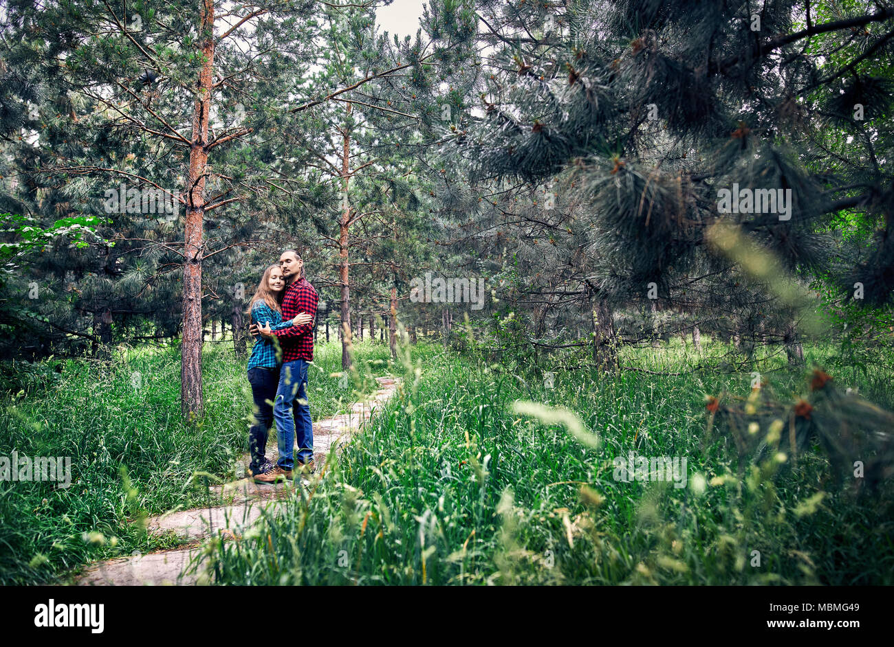 Young hipster couple in checkered shirt hugging in the pine tree forest. Love in the nature. Stock Photo