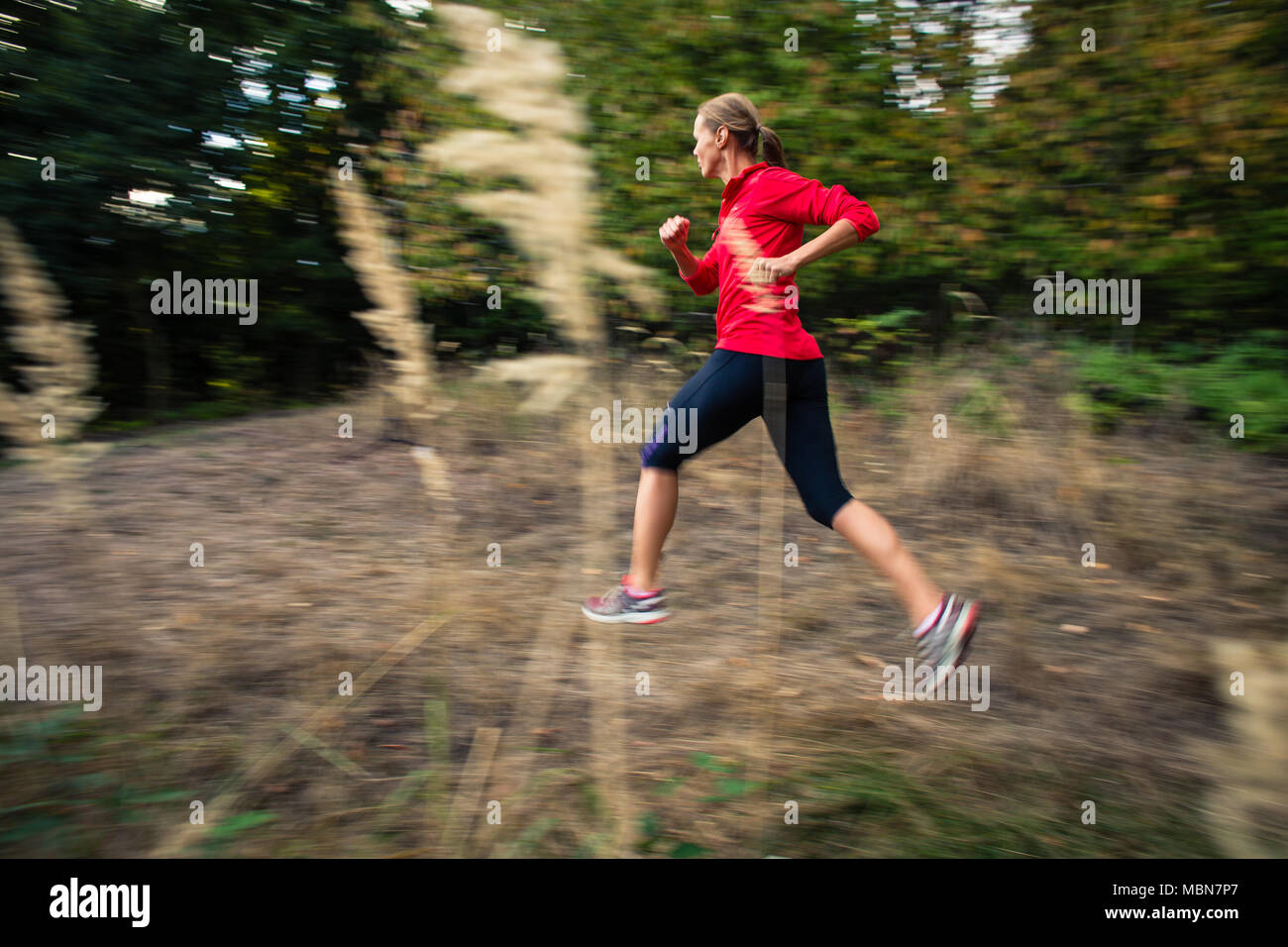 Young woman running outdoors in a forest, going fast (motion blurred ...
