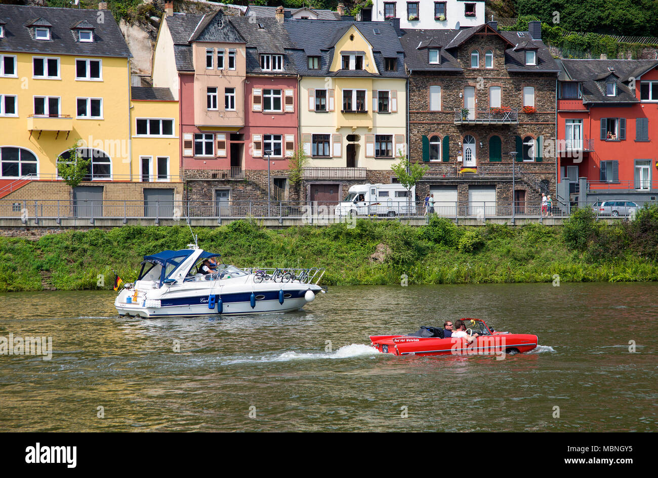 Amphic car, a german amphibious vehicle driving next to a motor boat on Moselle river at Cochem, Rhineland-Palatinate, Germany Stock Photo