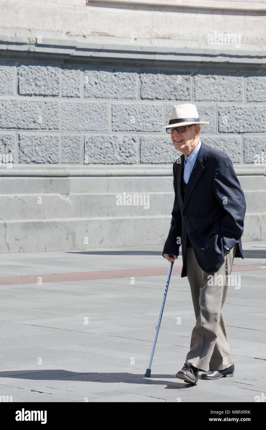 Stylish elderly man in jacket and trousers walking the plaza. Fit health old man in fashion clothing outside walking Stock Photo