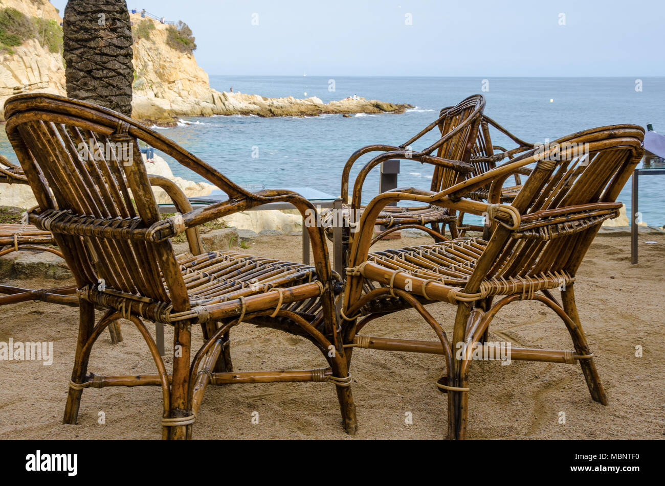 https://c8.alamy.com/comp/MBNTF0/bamboo-chairs-set-out-with-a-picturesque-view-of-the-sea-at-lloret-de-mar-in-the-costa-brava-region-of-spain-MBNTF0.jpg