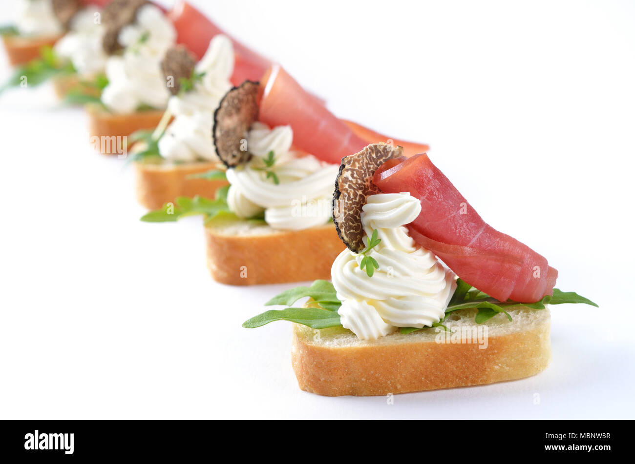 Yummy morsels with spiced cream cheese, ham, rucola and Italian black truffles Stock Photo