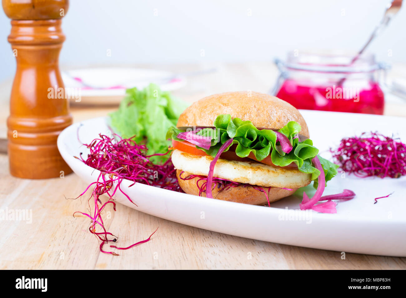 Halloumi burger with lettuce, tomato, pickled red onion and beet sprouts. Stock Photo