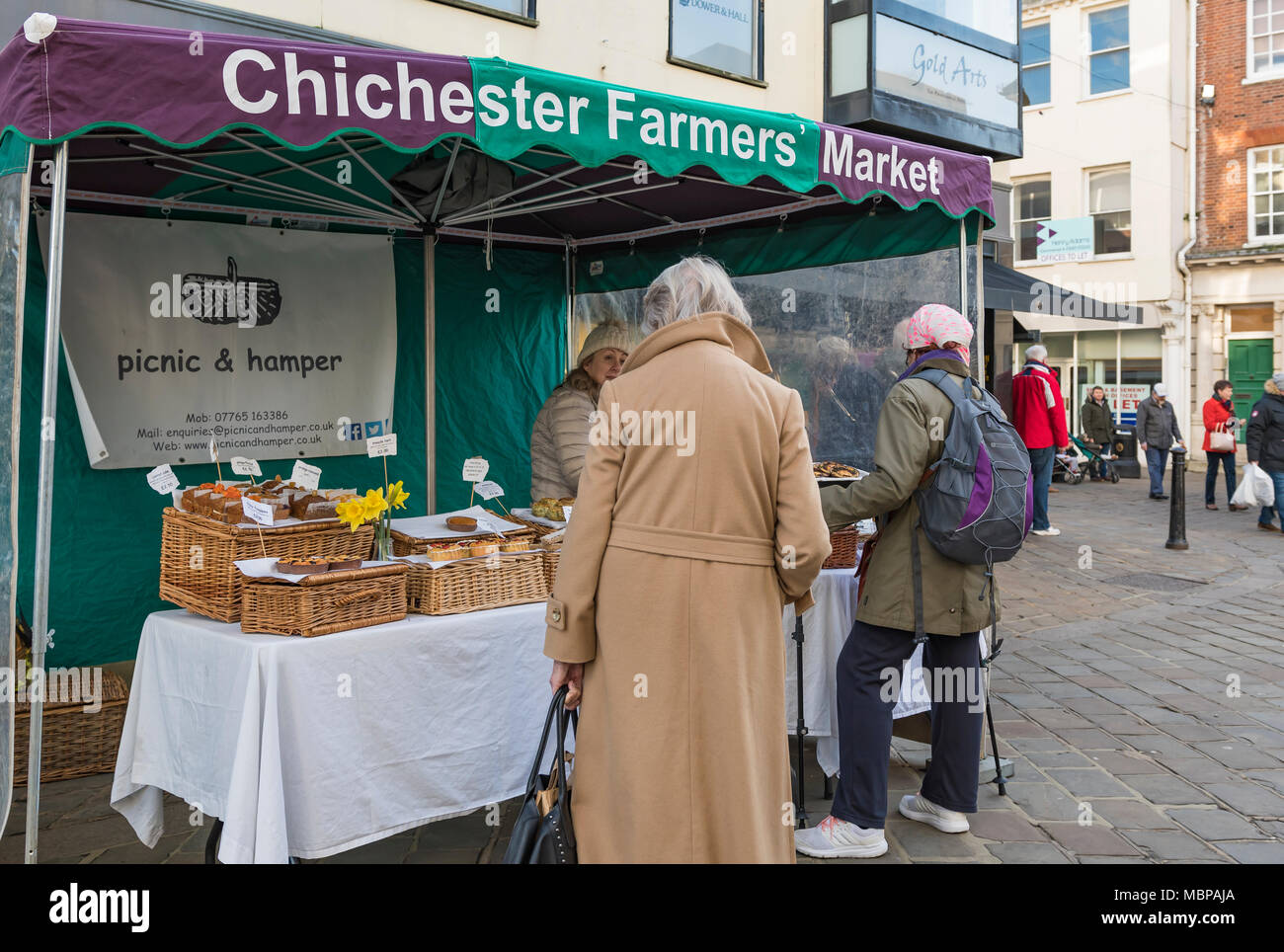 People shopping outside at a market stall at the Chichester Farmers' Market in the shopping centre in Chichester, West Sussex, England, UK. Stock Photo
