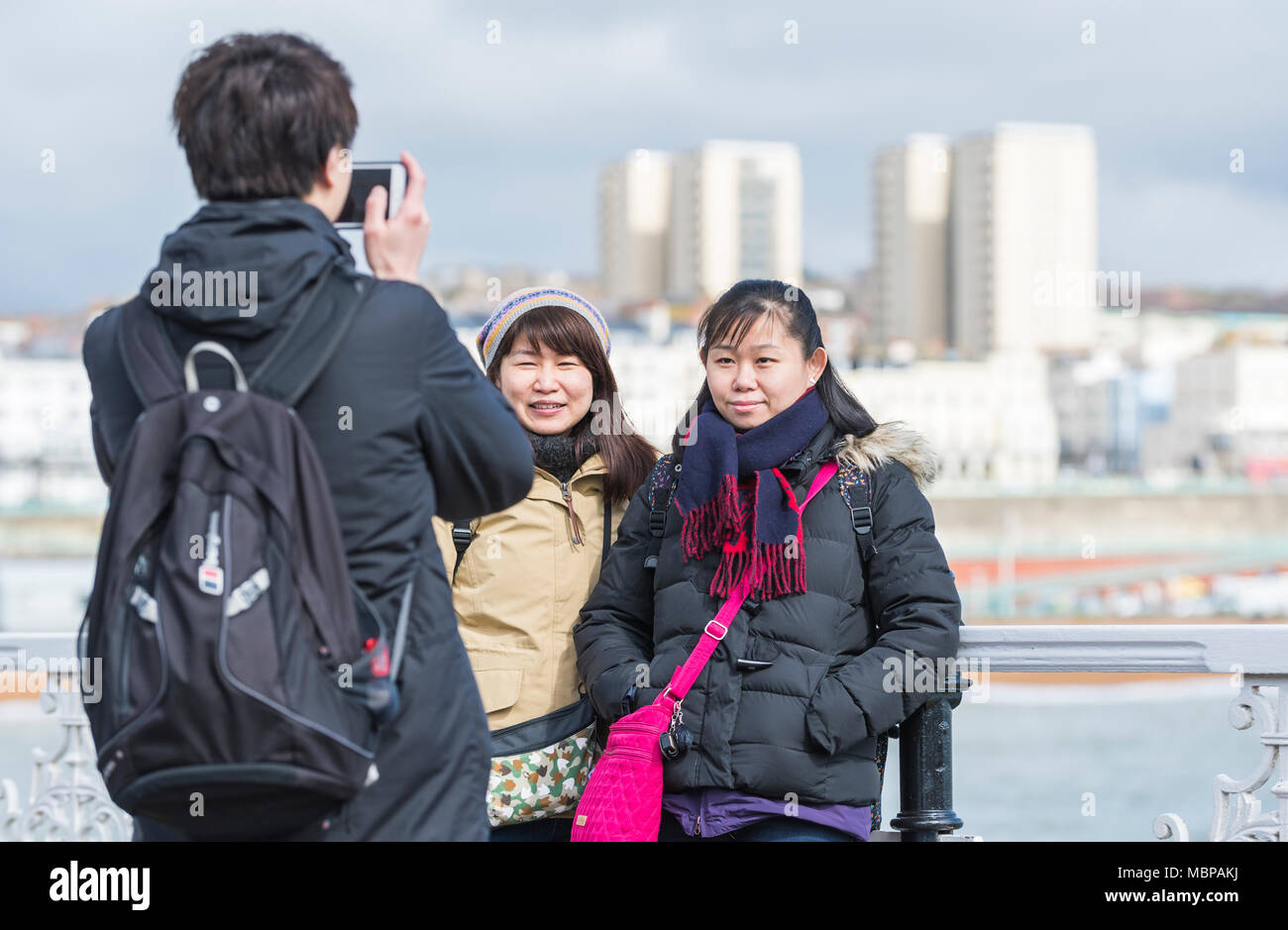 Japanese tourists having photo taken at the seaside in Brighton, East Sussex, England, UK. Stock Photo