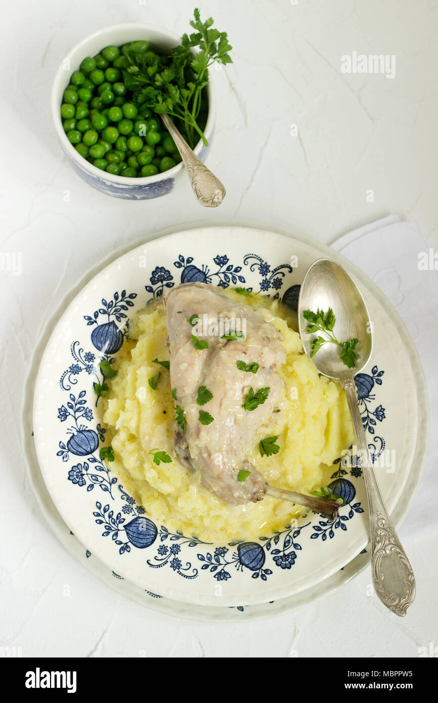 Rabbit in sour cream sauce with tender mashed potatoes and green peas. Rustic style. Stock Photo