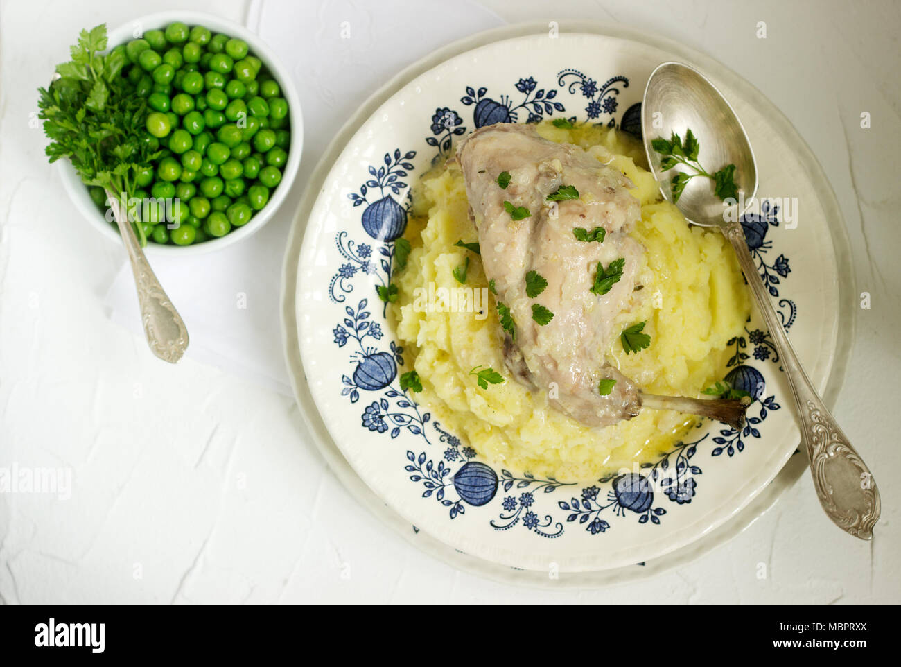 Rabbit in sour cream sauce with tender mashed potatoes and green peas. Rustic style Stock Photo