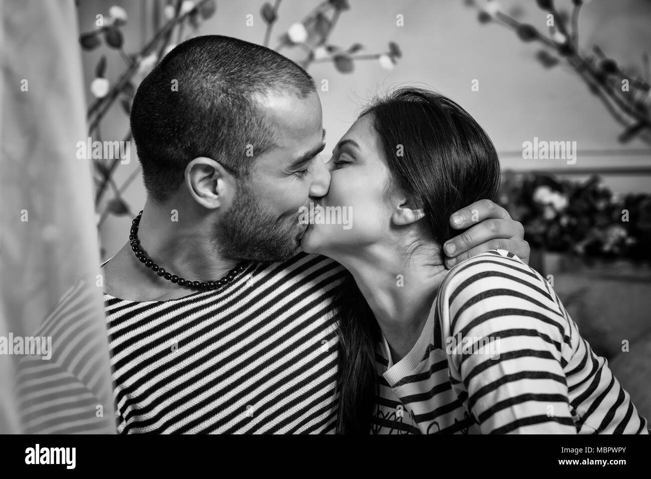 https://c8.alamy.com/comp/MBPWPY/black-and-white-photo-of-charming-international-couple-in-striped-sweaters-kissing-and-hugging-while-sitting-on-the-bed-in-the-bedroom-MBPWPY.jpg