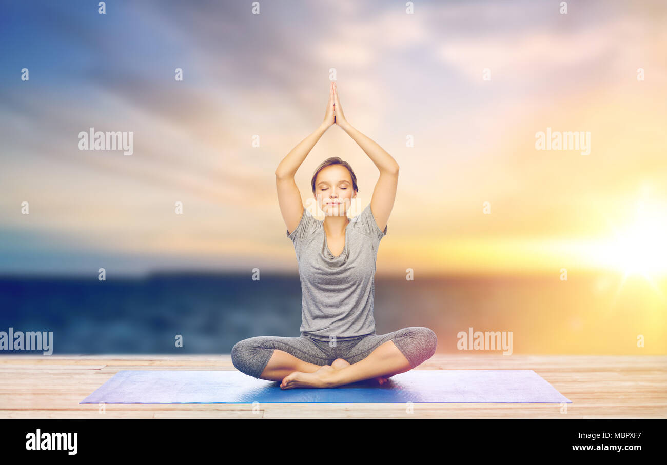 woman meditating in lotus pose on mat outdoors Stock Photo