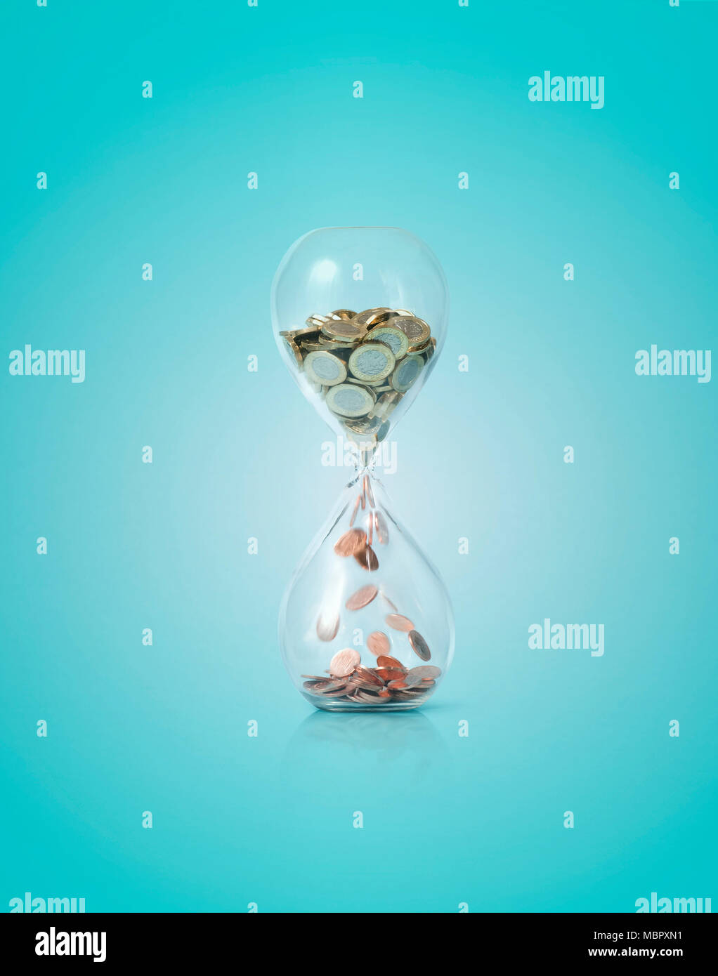 An hour glass containing pound coins and pennies Stock Photo