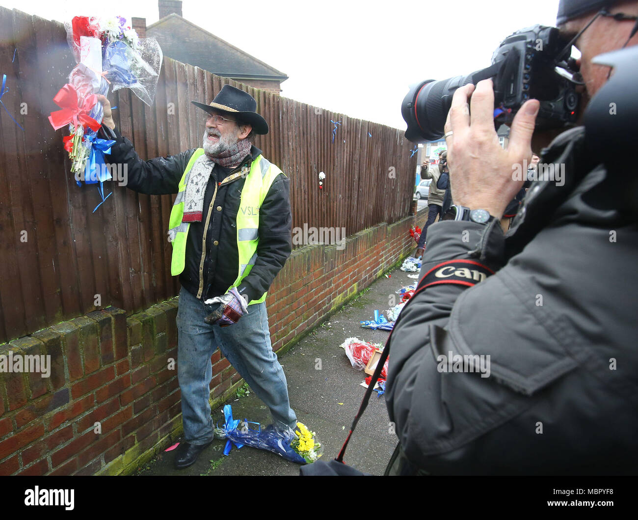 Iain Gordon pulls the flowers down from a fence opposite the house of Richard Osborn-Brooks in South Park Crescent in Hither Green, London, after it has become an unlikely flashpoint of tensions between the grieving family and his neighbours since last week's incident after burglar Henry Vincent was killed by Richard Osborn-Brooks at his house. Stock Photo