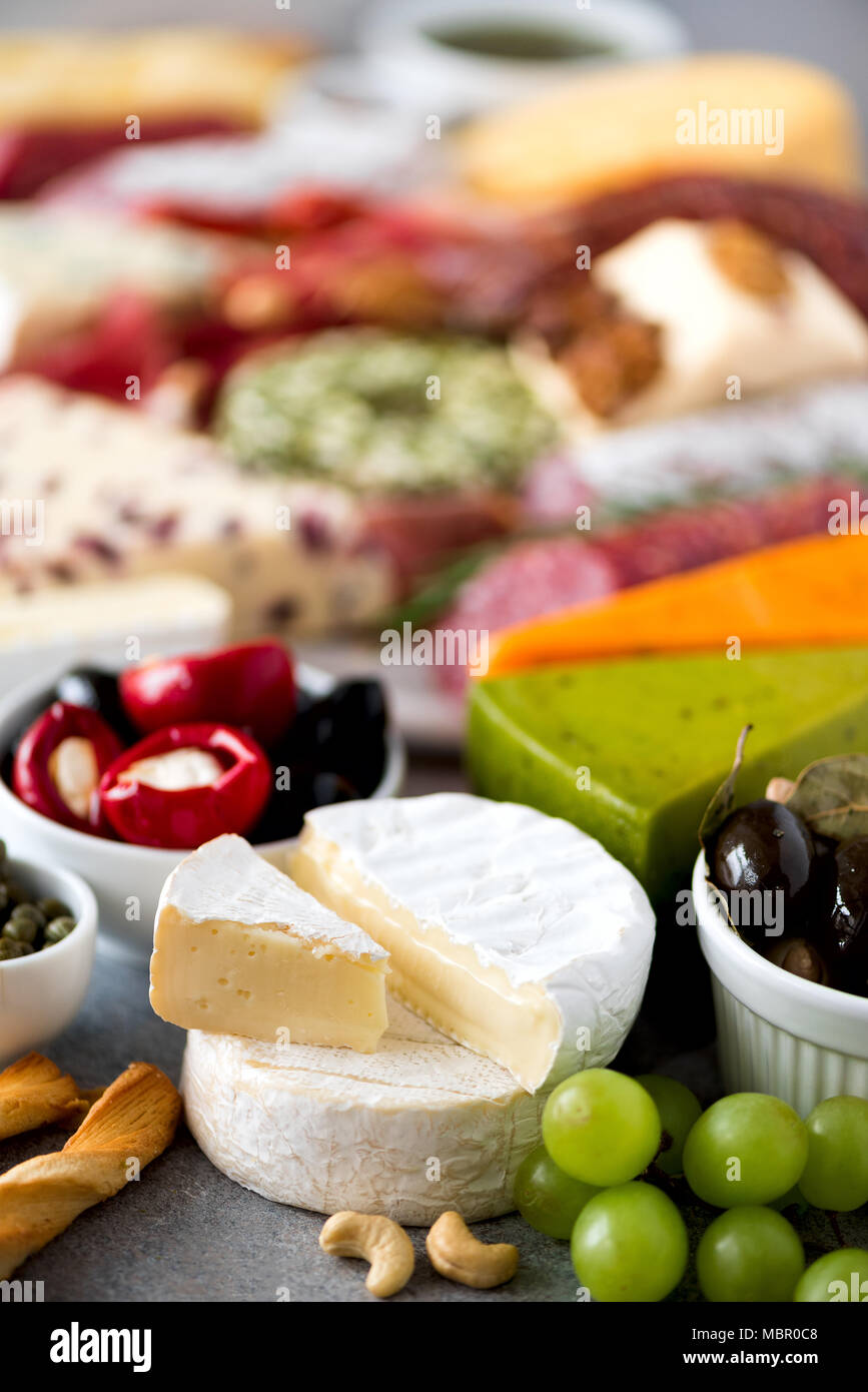 Assortment of hard, semisoft and soft cheeses with olives, grissini