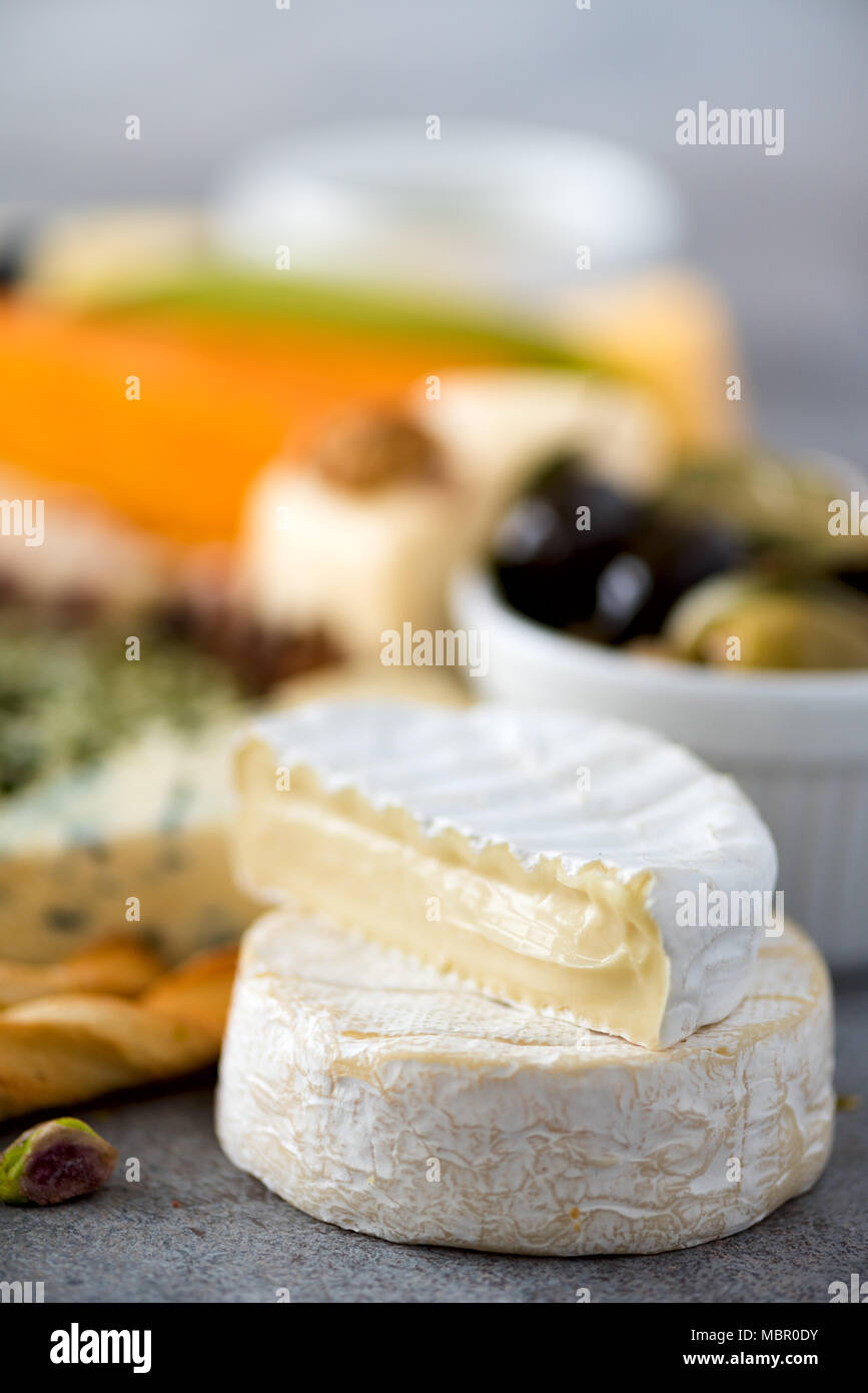Assortment of hard, semisoft and soft cheeses with olives, grissini