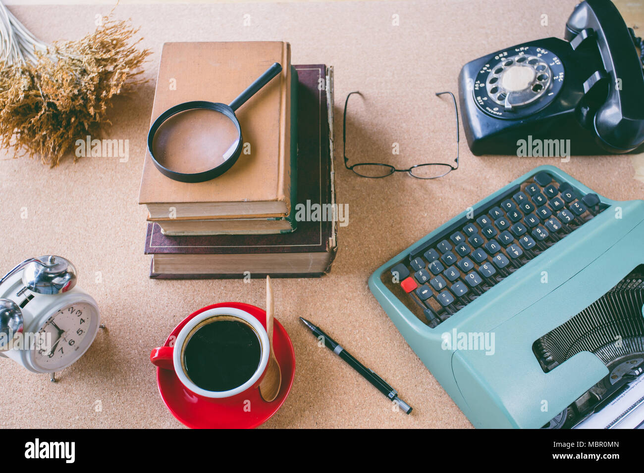 A magnifying glass on stack book with accessories retro office  on table Stock Photo