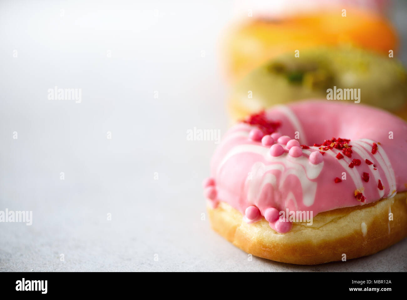Stack of glazed colorful assorted donuts with sprinkles on grey cement ...