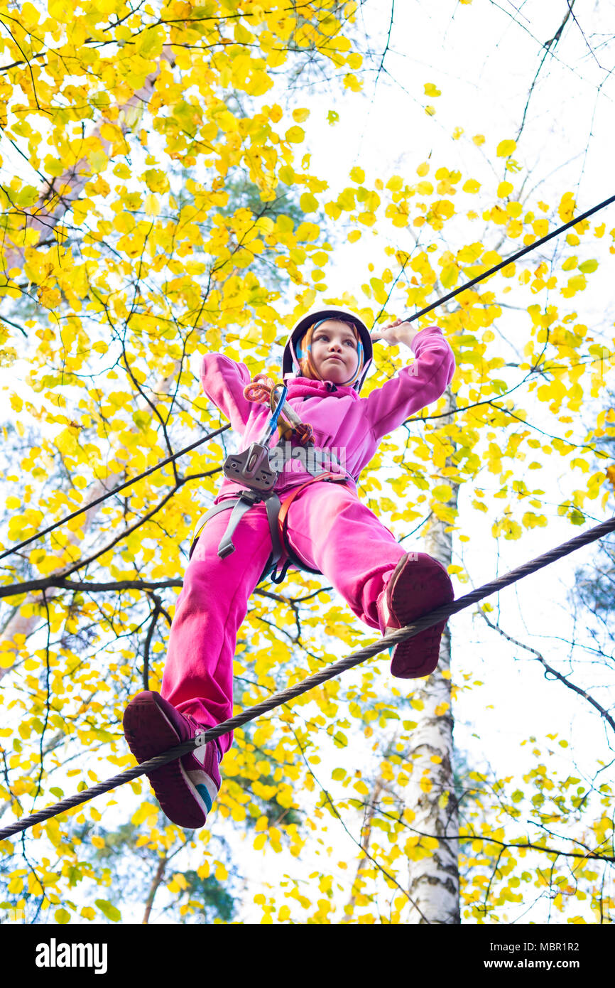 Young girl in harness climbing and trying facilities in an adventure