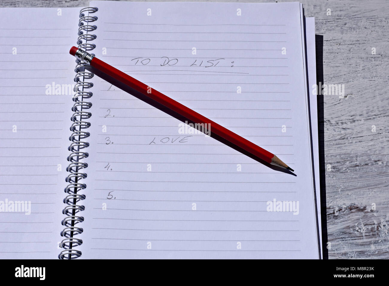 Red pencil with notebook on wooden table Save creative ideas on paper. Basic equipment before the computer. On the rustic table background Stock Photo