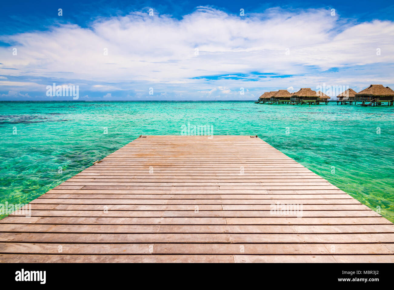 Wooden jetty or pier over tropical blue lagoon in Moorea, French Polynesia. Stock Photo