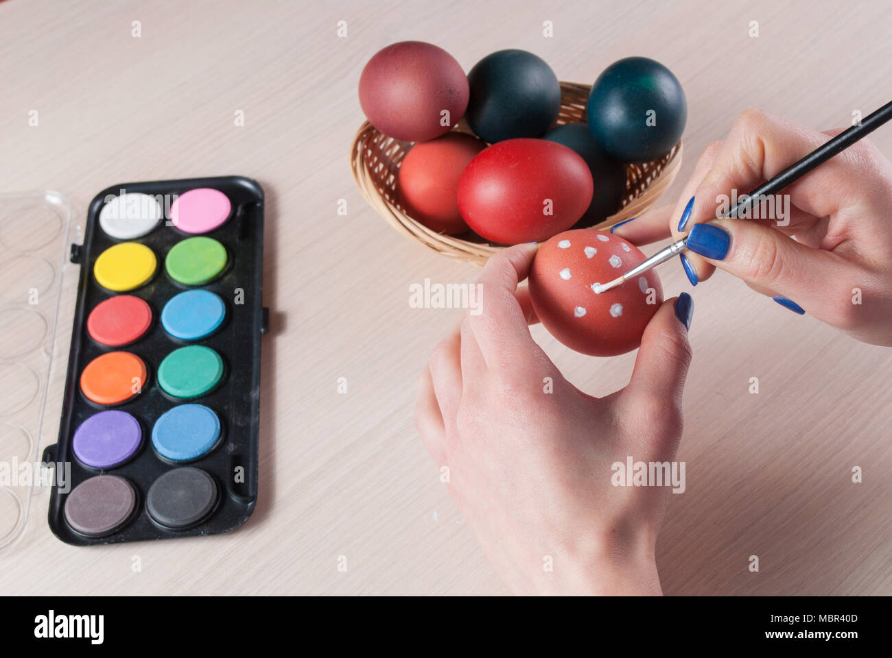 Closeup photo of woman holding egg and painting it with brush. Easter concept Stock Photo