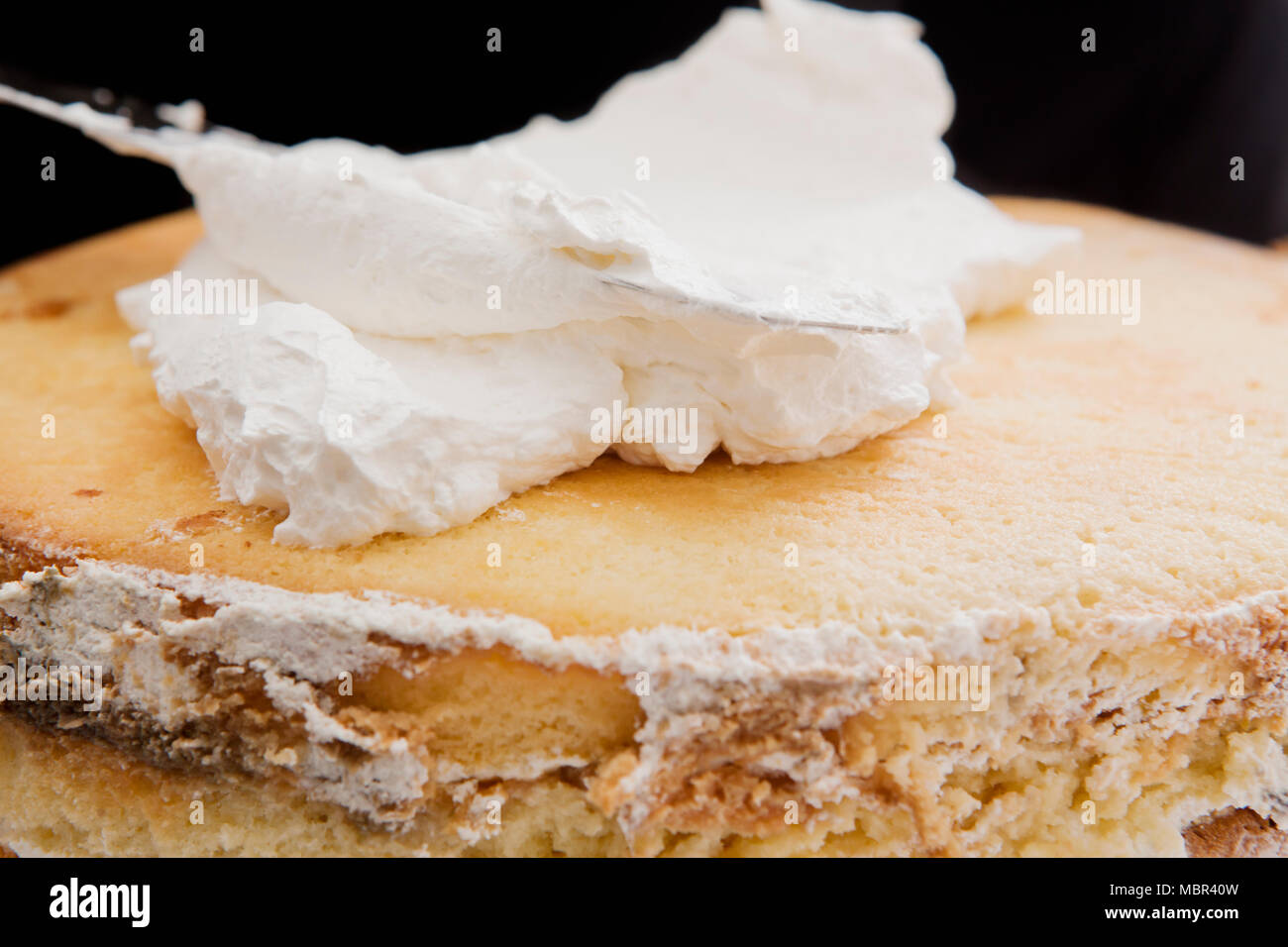 Sponge Cake being Iced with white cream on a spatula Stock Photo