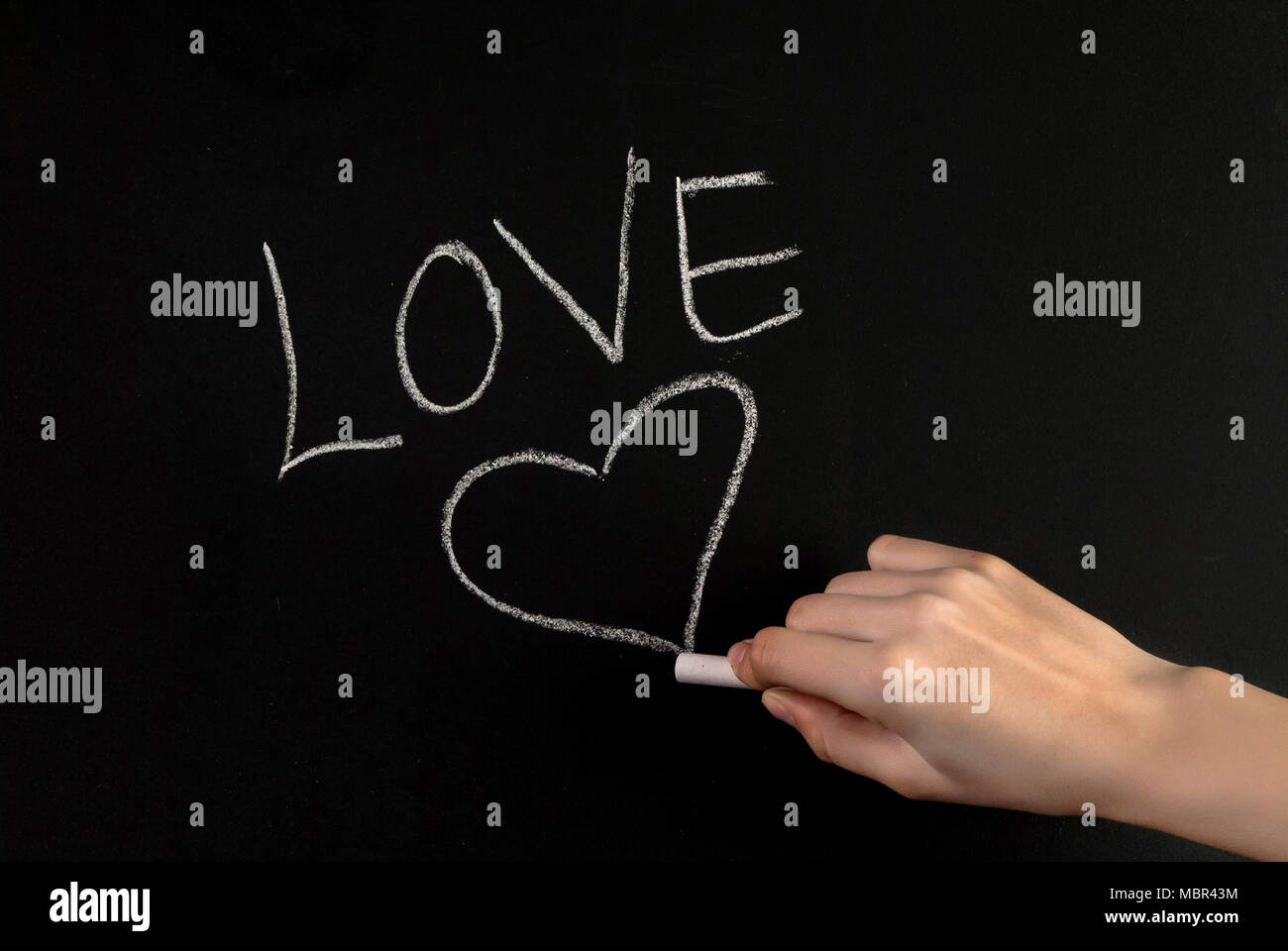 Girl Hand Write Word Love And Drawing Heart On Blackboard With White Chalk Girl Hand Write Word Love And Drawing Heart On Blackboard With White Chalk