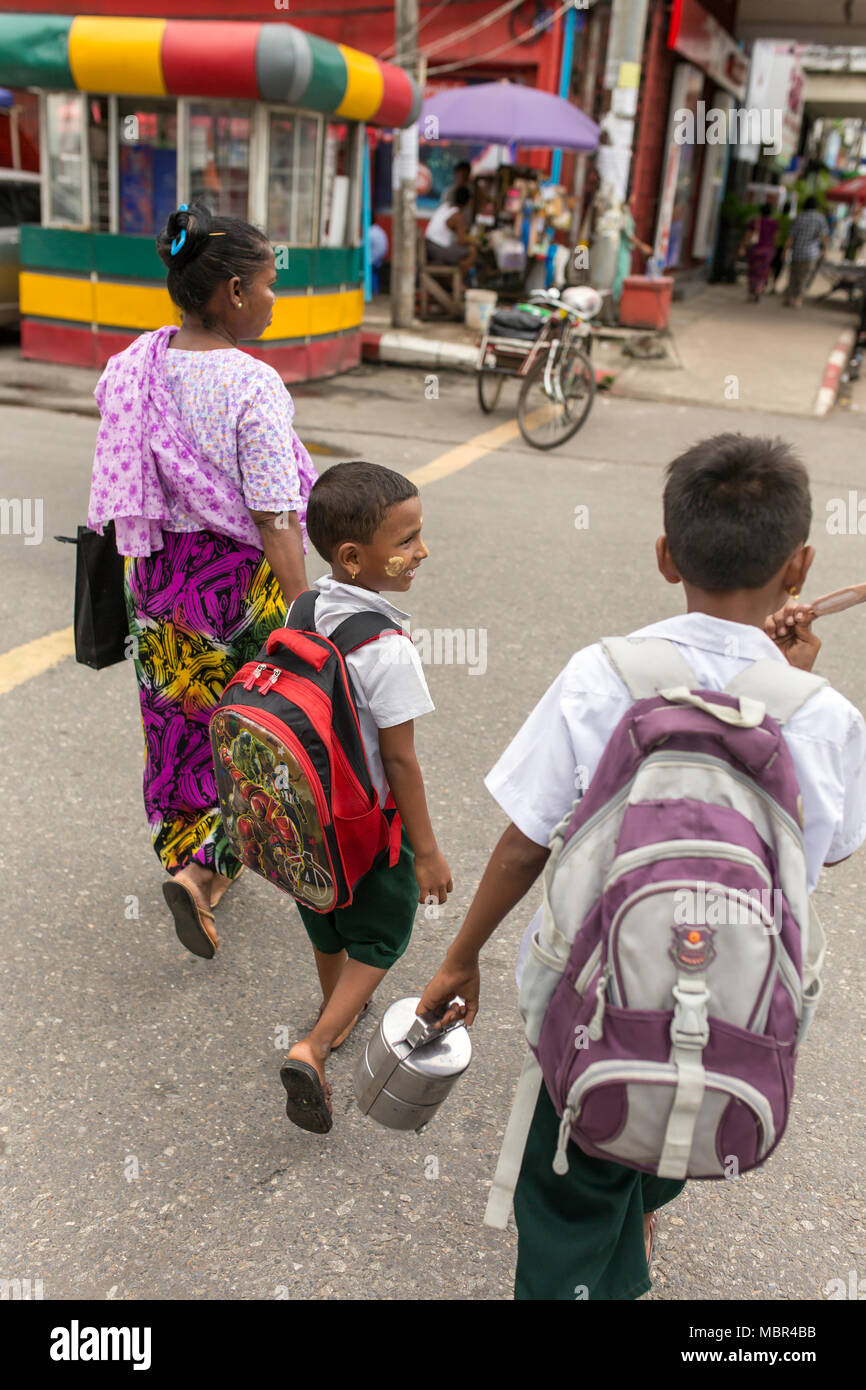 Yangon, Myanmar - September 26, 2016: Unidentified burmese woman taking her kids to school. Yangon street scene. Stock Photo
