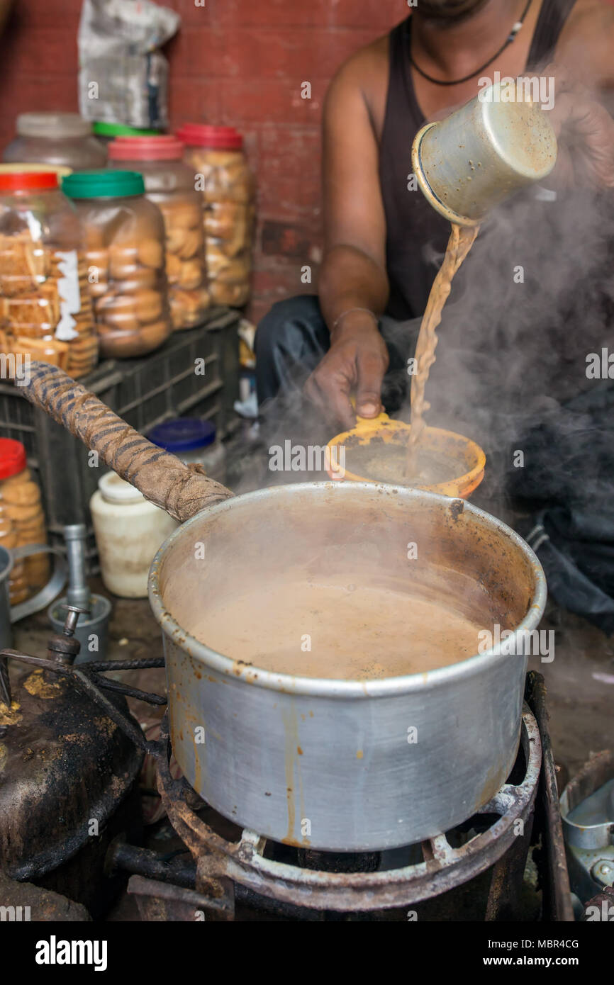 Man pour cup of hot milk tea Indian style or chai for customers in his shop along the street in Kolkata, India Stock Photo
