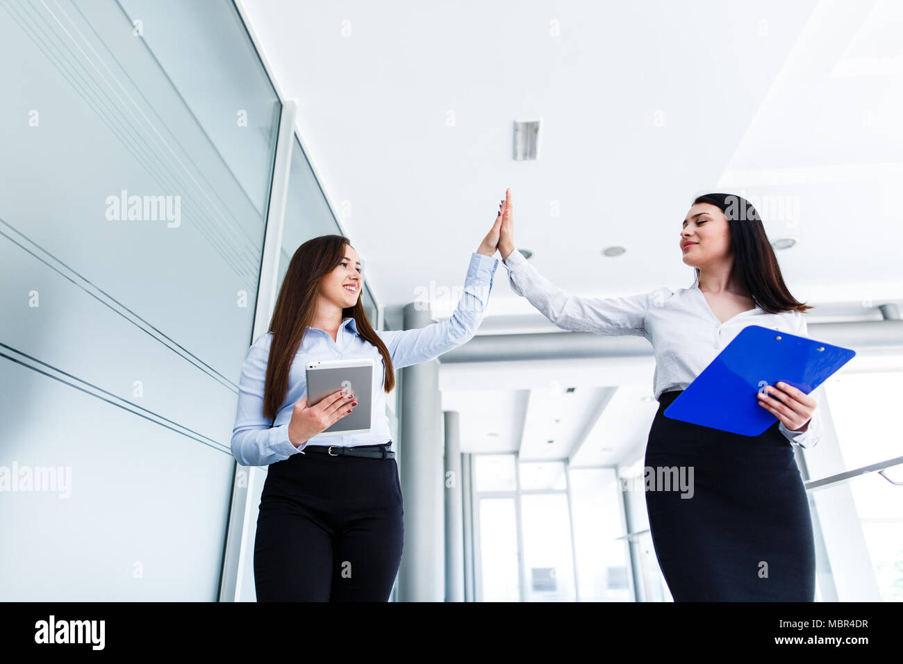 Business womens doing high five in modern interior Stock Photo