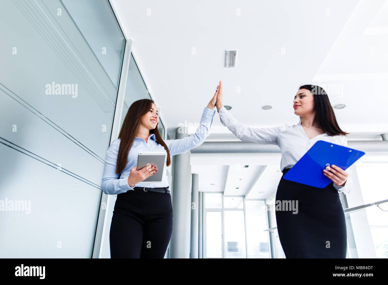 Business womens doing high five in modern interior Stock Photo