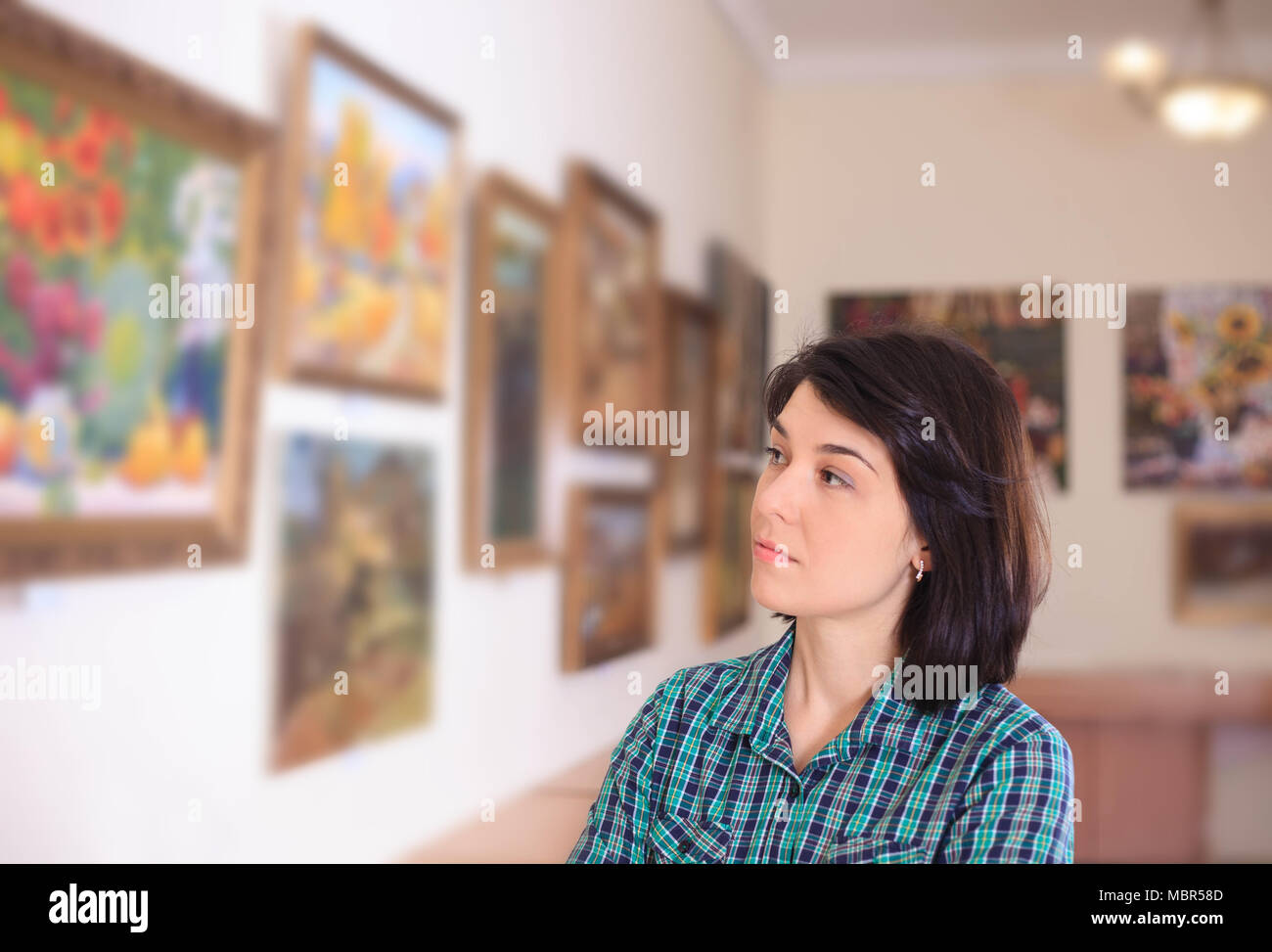 Young woman looking at painting in art gallery Stock Photo - Alamy
