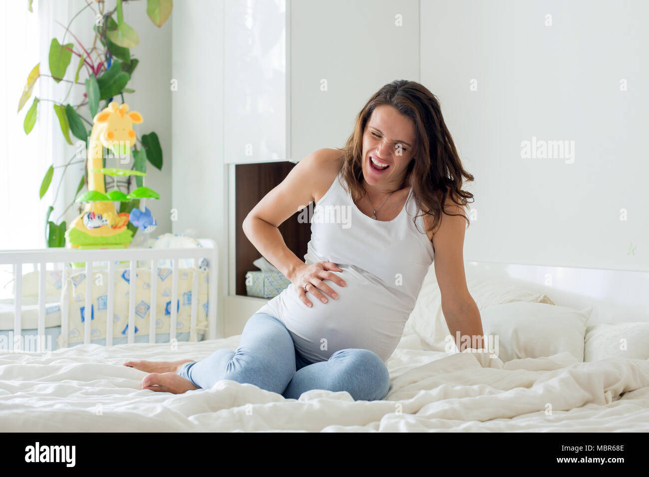 Young beautiful pregnant woman, in pain with labor contraction, sitting