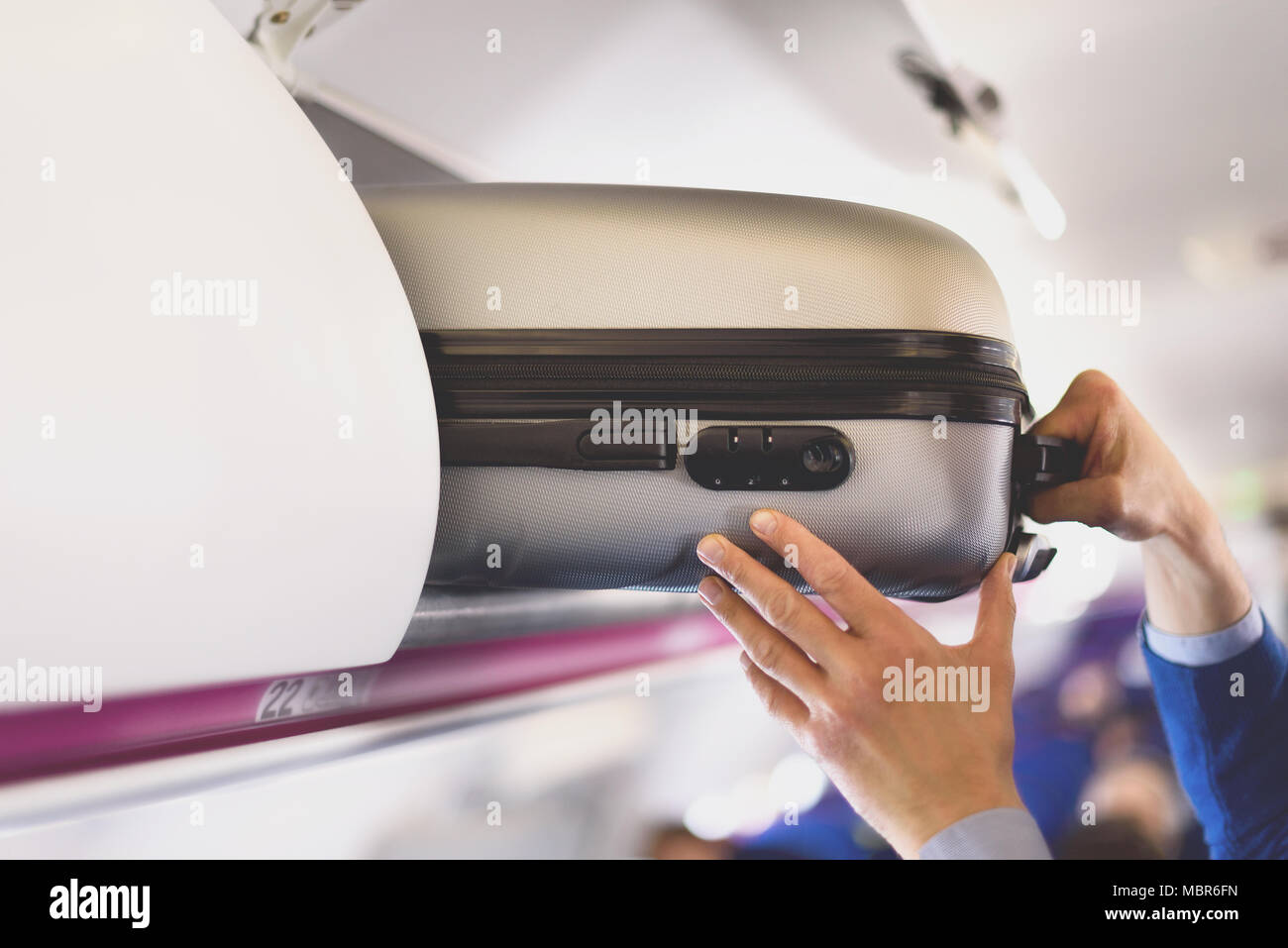Handluggage compartment with suitcases in airplane. Hands take off
