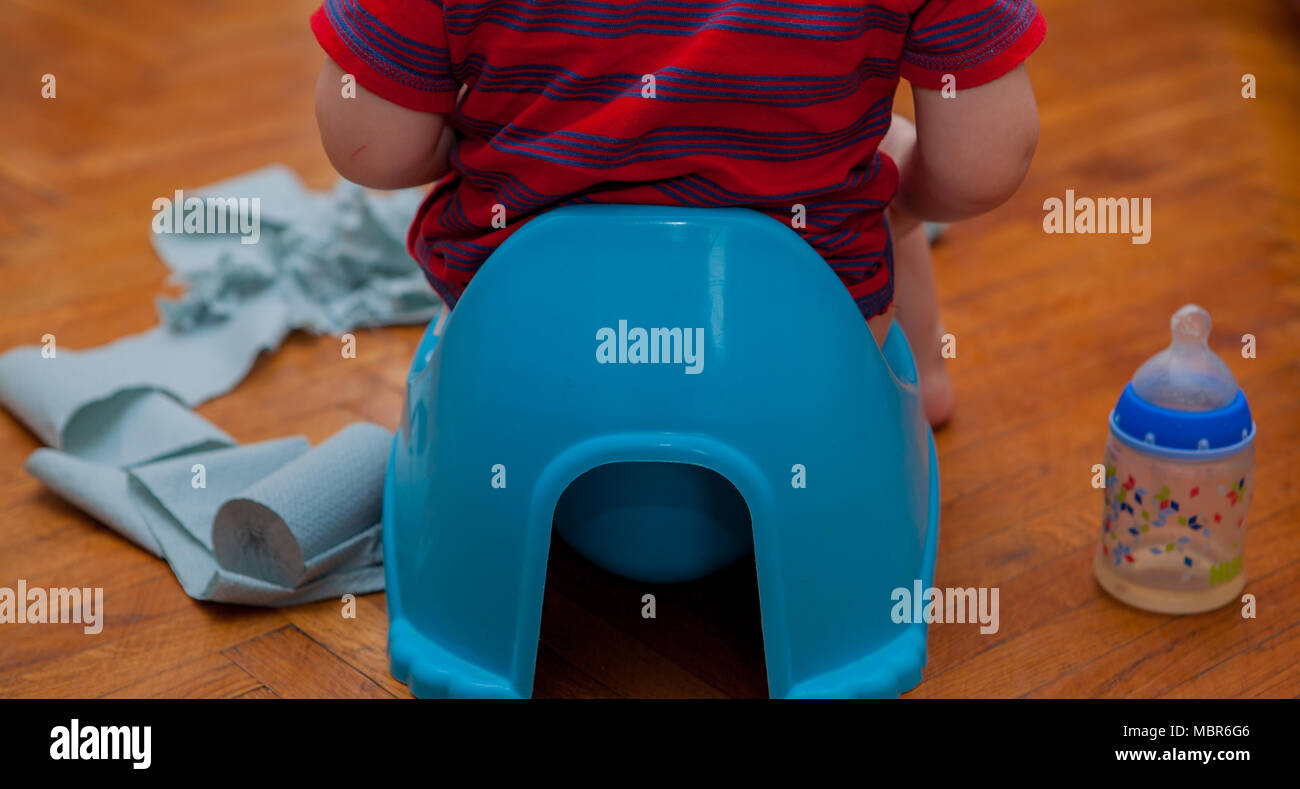 little baby sitting on chamber pot with toilet paper and pacifier on a ...