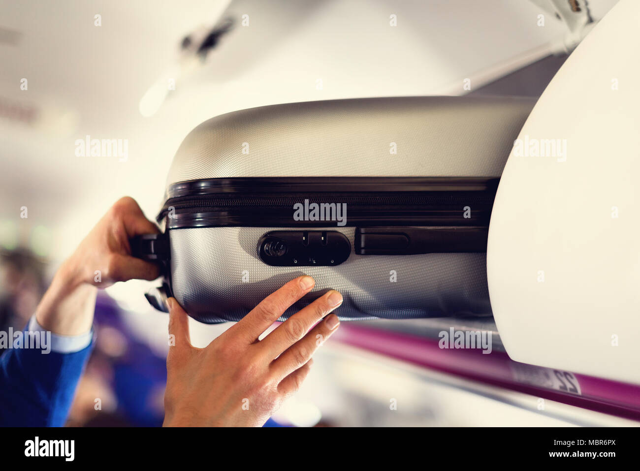 Handluggage compartment with suitcases in airplane. Hands take off
