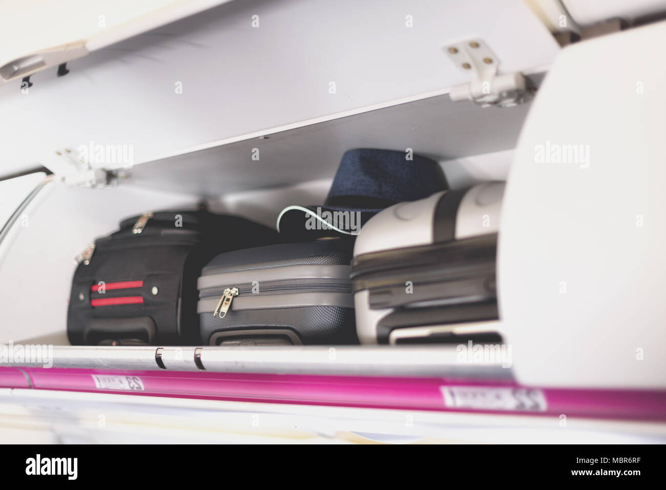Hand-luggage compartment with suitcases in airplane. Carry-on luggage on  top shelf of plane. Travel concept with copy space Stock Photo - Alamy