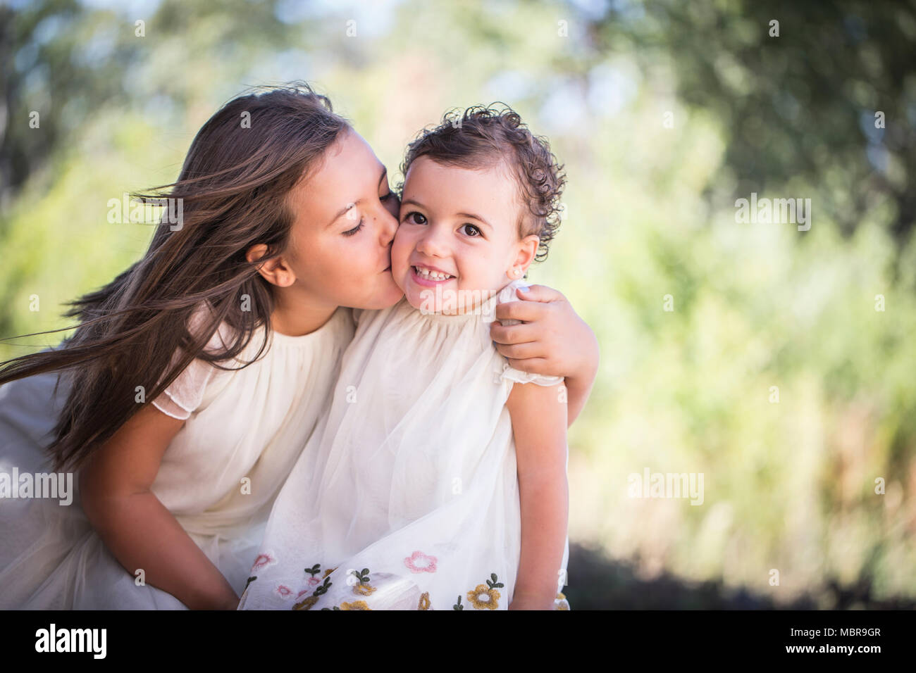 Siblings, big sister gives little sister a kiss Stock Photo