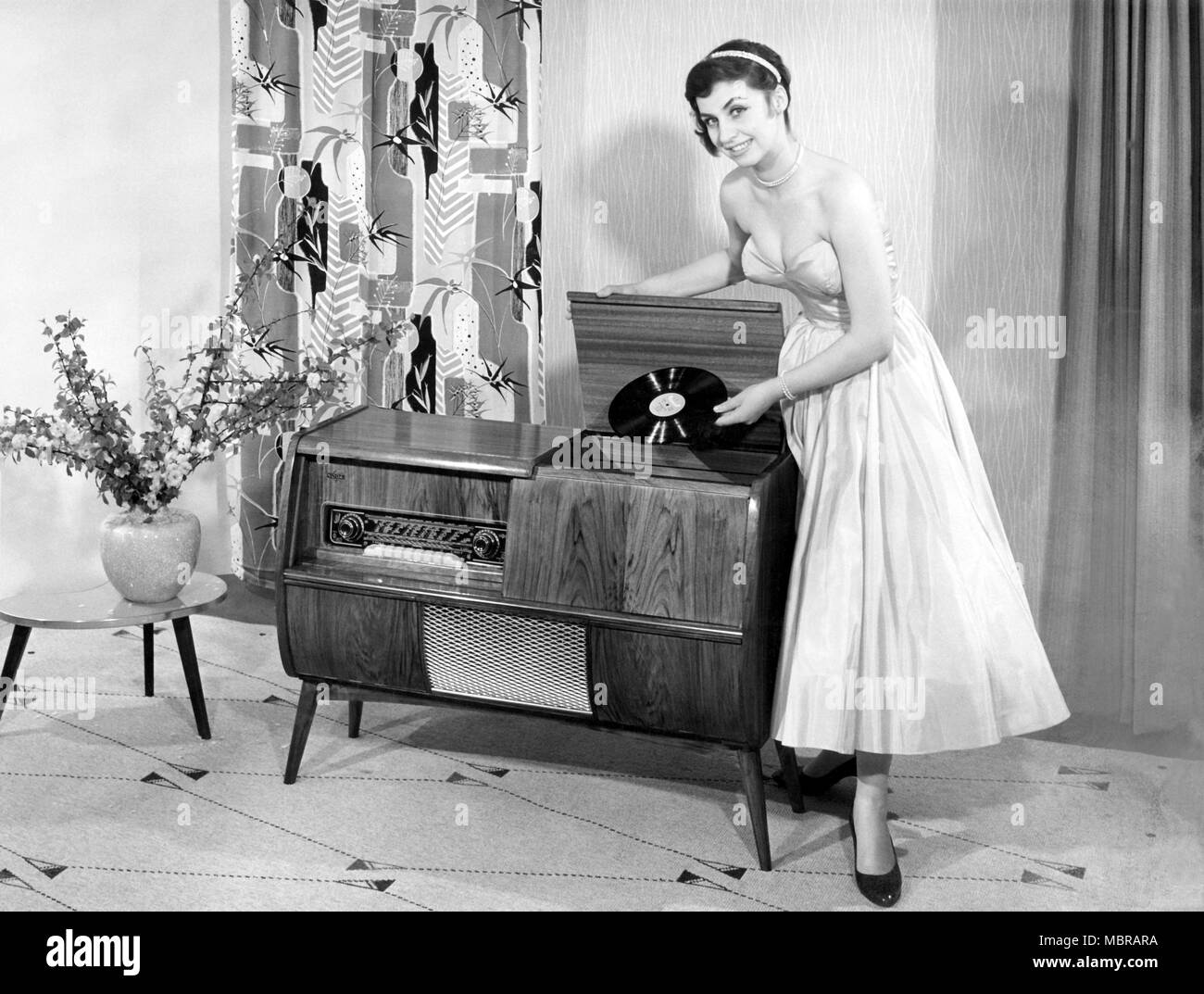 Woman in front of a record player in the living room, 1950s, Germany Stock Photo