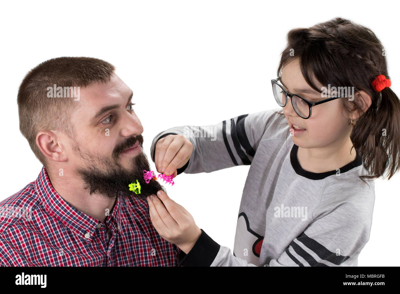 Father and daughter playing together. Girl is playing with her dad and making his hairstyle. Isolated on white. Stock Photo