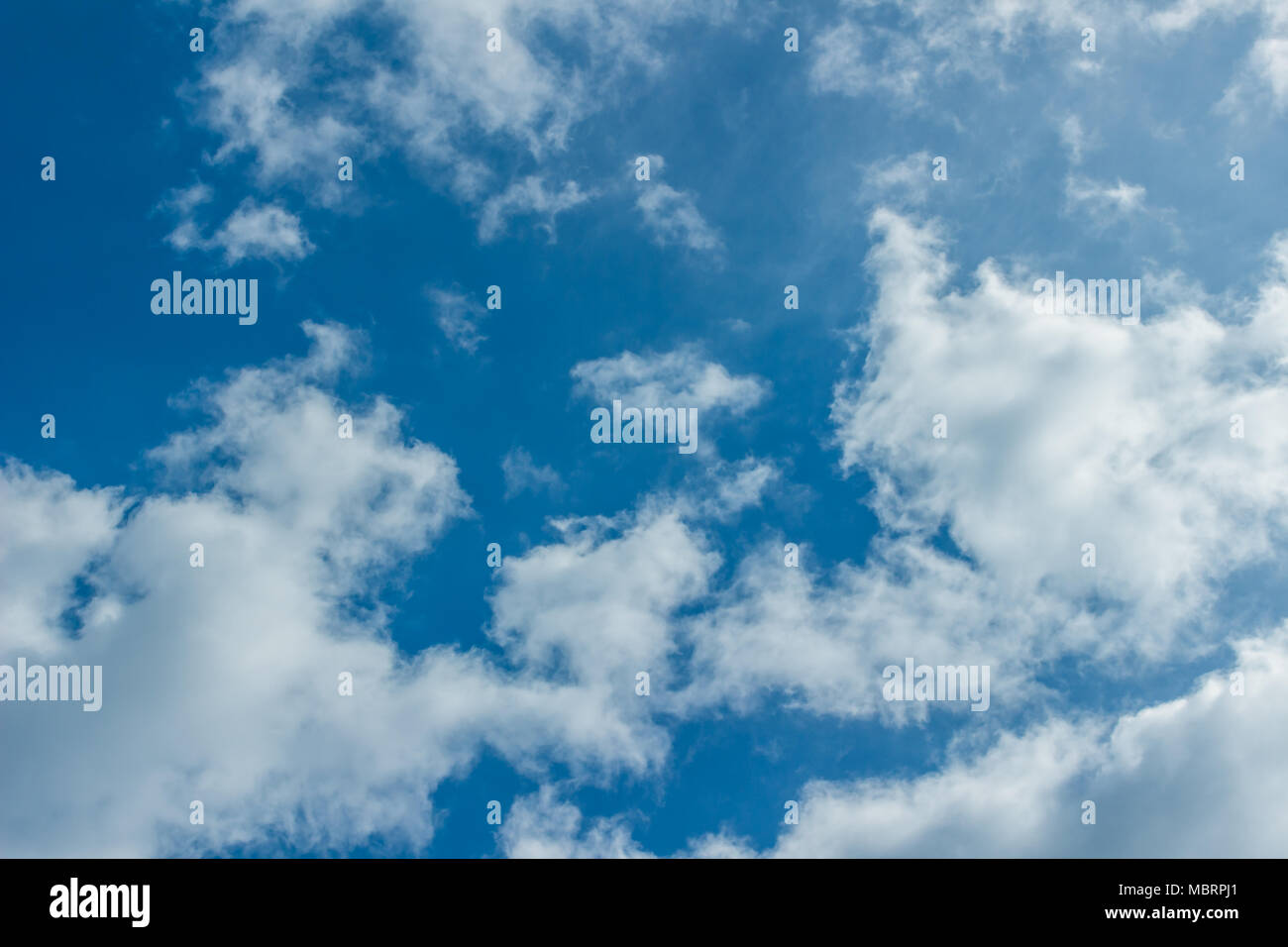 White puffy clouds on a light blue sky background Stock Photo - Alamy