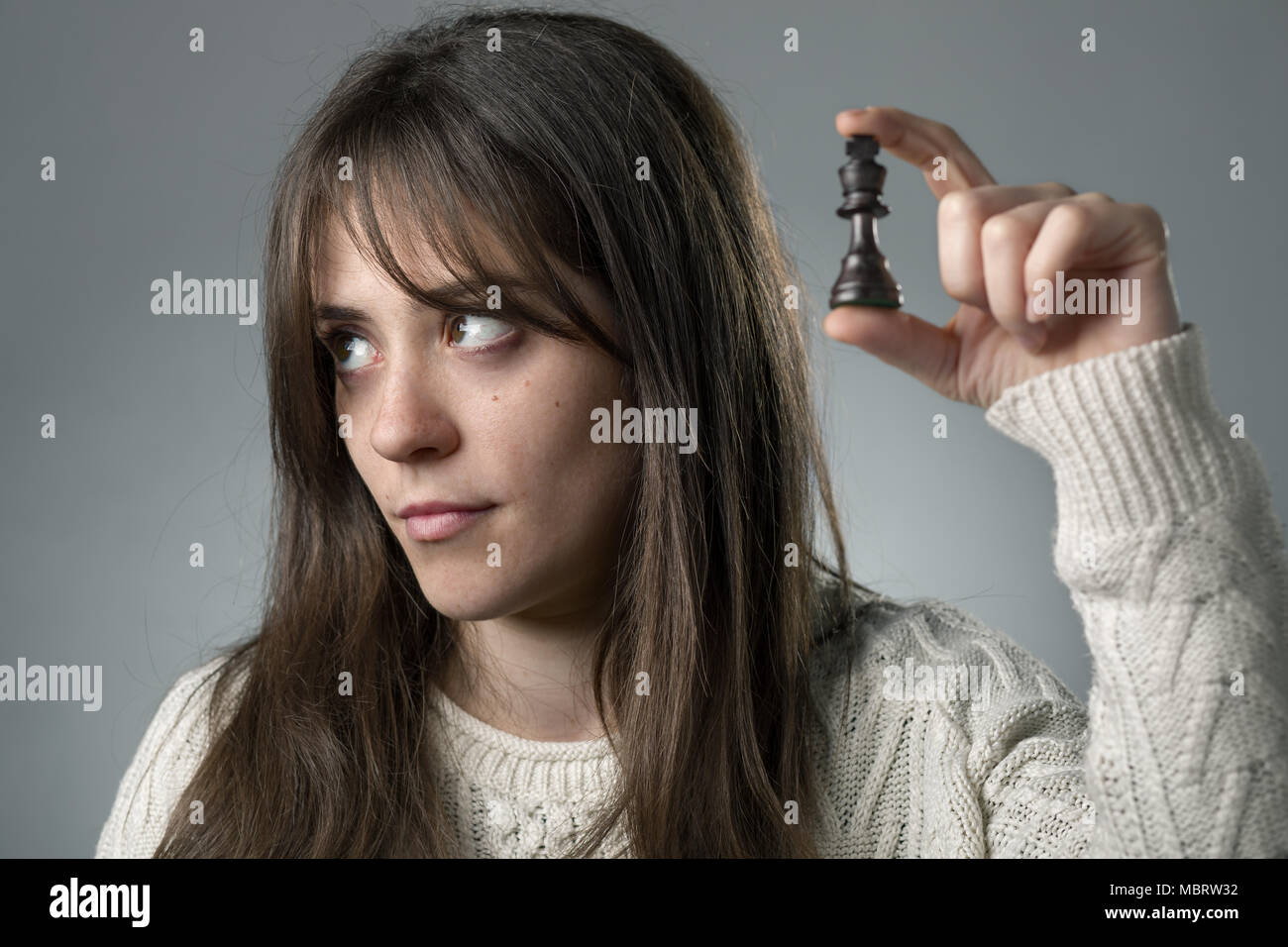 Bored Woman Holding a King Chess Piece with Her Hand Stock Photo