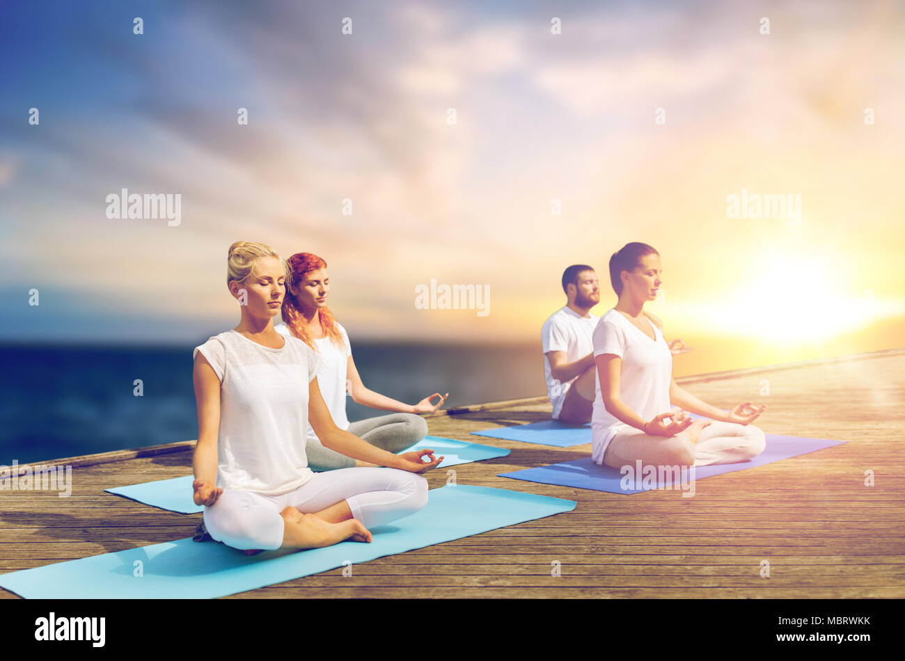 people meditating in yoga lotus pose outdoors Stock Photo