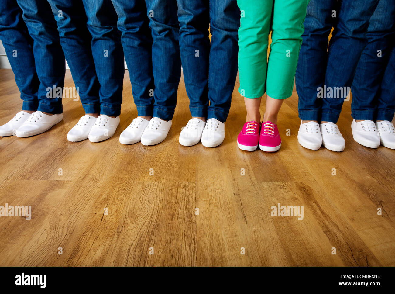 Woman in pink shoes standing in a row of people wearing white shoes Stock Photo