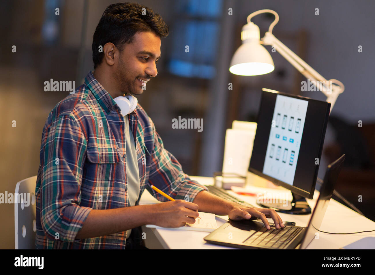 creative man with laptop working at night office Stock Photo - Alamy