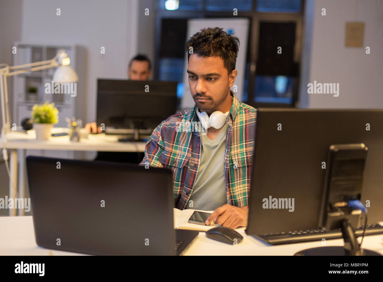 creative man with laptop working at night office Stock Photo - Alamy